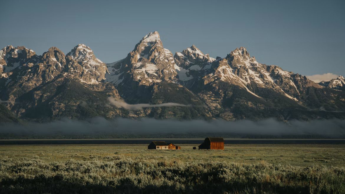 The Grand Tetons at dawn with a barn in the sagebrush